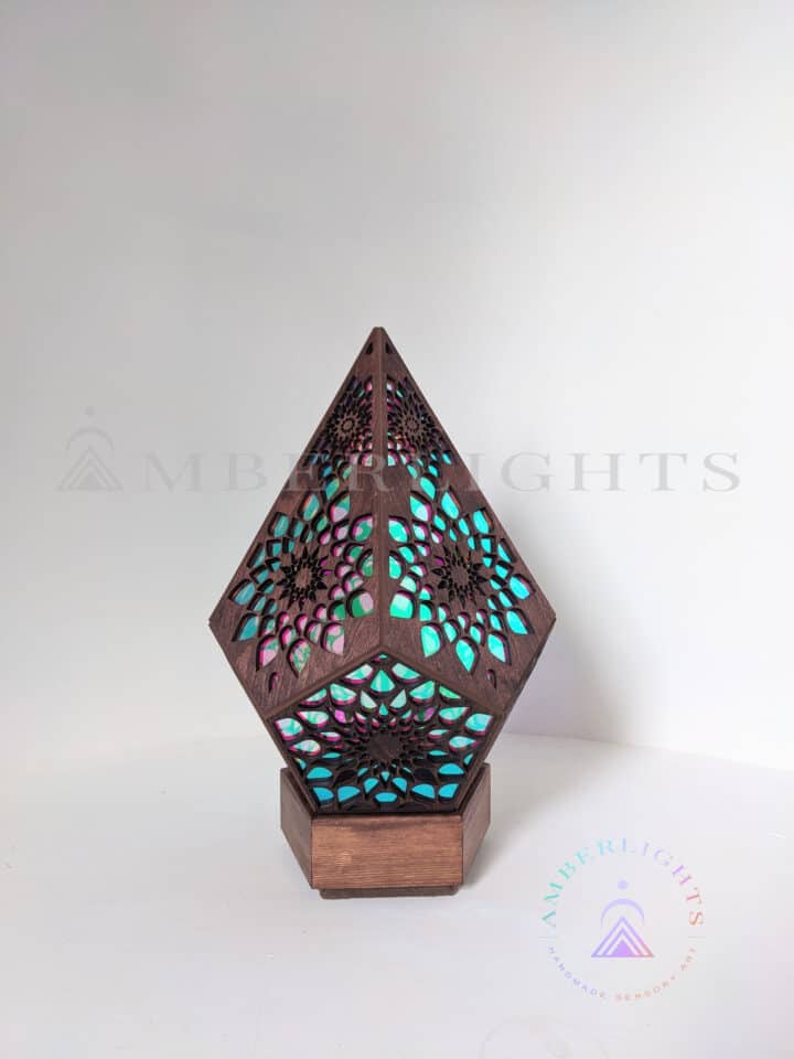 Handcrafted pyramid-shaped sensory lamp by AmberLights, adorned with intricate multicolored patterns casting vibrant kaleidoscopic projections onto surrounding surfaces