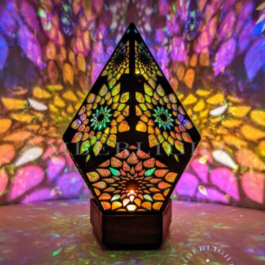 Handcrafted pyramid-shaped sensory lamp by AmberLights, adorned with intricate multicolored patterns casting vibrant kaleidoscopic projections onto surrounding surfaces.
